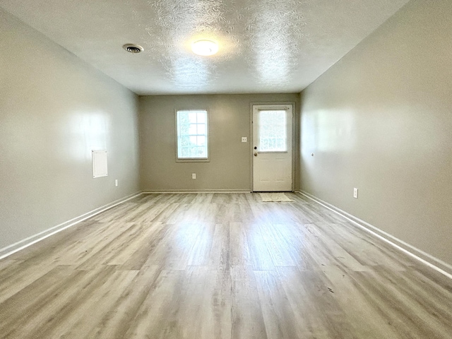 empty room with a textured ceiling and light wood-type flooring