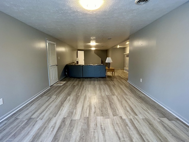 unfurnished living room with a textured ceiling and light hardwood / wood-style floors