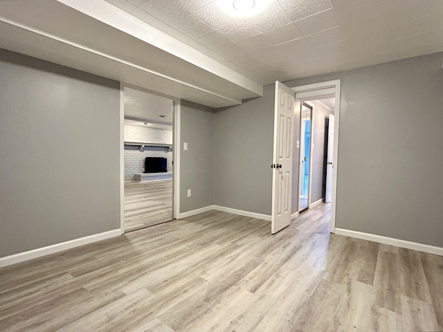 spare room with light hardwood / wood-style flooring and brick wall