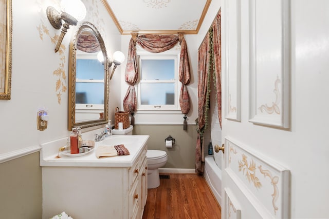 full bathroom featuring hardwood / wood-style floors, vanity, shower / tub combo, and toilet