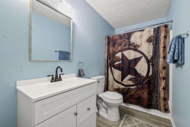 bathroom with wood-type flooring, oversized vanity, toilet, and a textured ceiling