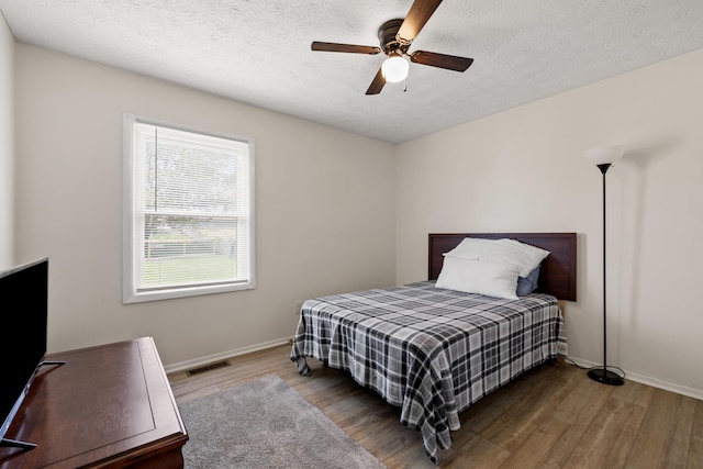 bedroom with ceiling fan, a textured ceiling, and wood-type flooring