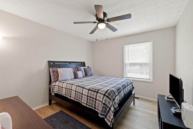 bedroom with ceiling fan, light hardwood / wood-style floors, and a textured ceiling