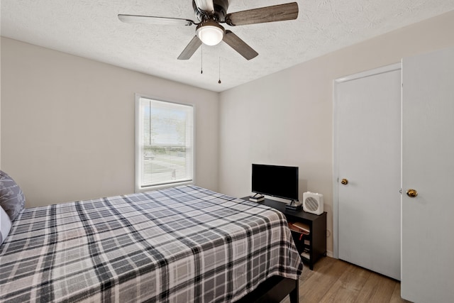 bedroom featuring a textured ceiling, light wood-type flooring, and ceiling fan