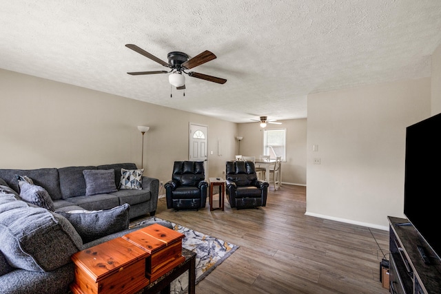 living room featuring hardwood / wood-style flooring, ceiling fan, and a textured ceiling