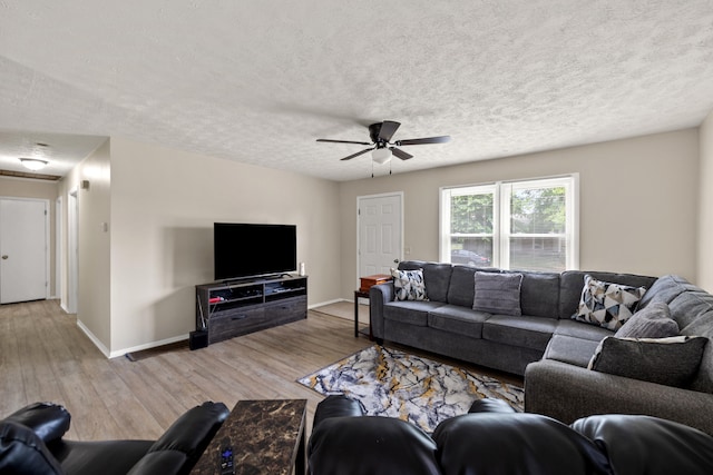 living room featuring ceiling fan, light hardwood / wood-style flooring, and a textured ceiling