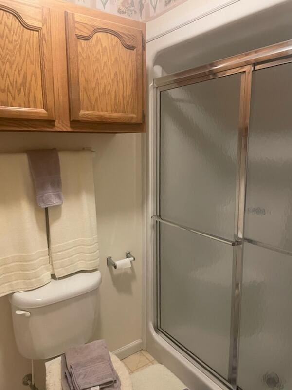 bathroom featuring toilet and a shower with door