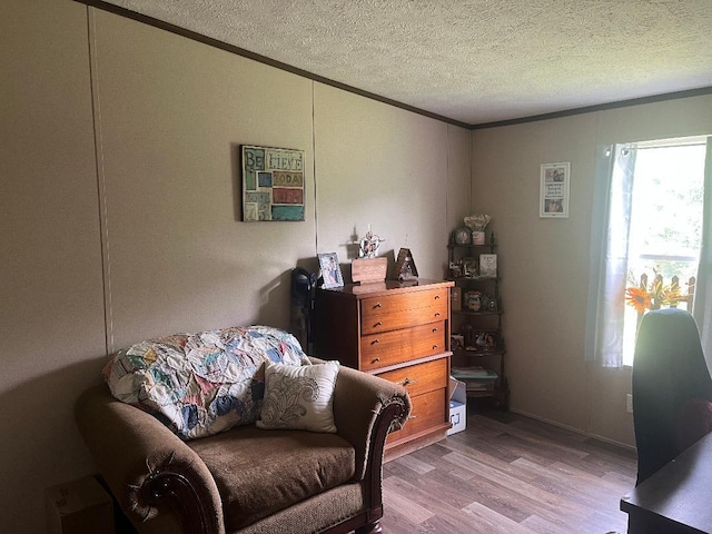 sitting room with crown molding, a textured ceiling, and light hardwood / wood-style flooring