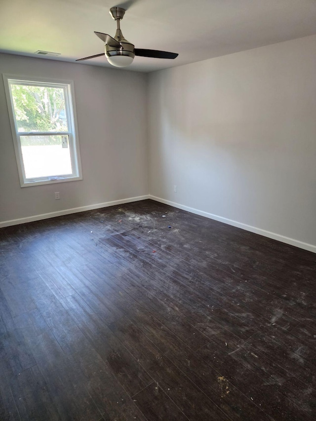 spare room featuring dark wood-type flooring and ceiling fan