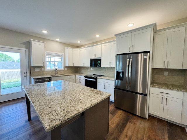 kitchen with white cabinetry, sink, a center island, light stone countertops, and appliances with stainless steel finishes