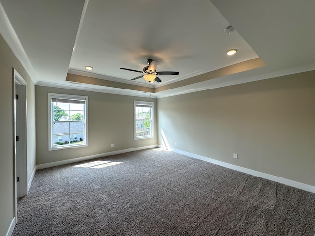 empty room with a tray ceiling, ceiling fan, and carpet flooring