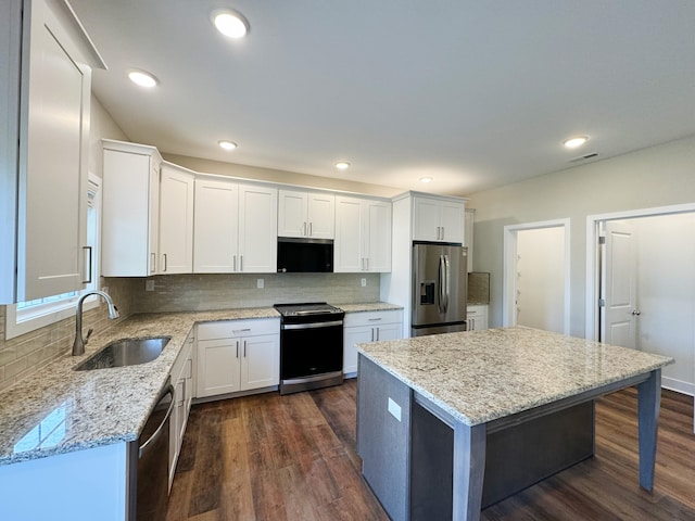 kitchen with dark wood-type flooring, white cabinets, light stone countertops, tasteful backsplash, and stainless steel appliances