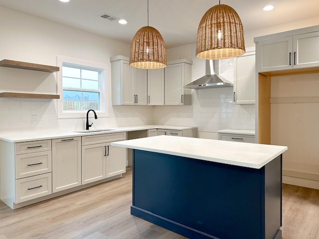 kitchen with light hardwood / wood-style floors, hanging light fixtures, sink, and backsplash