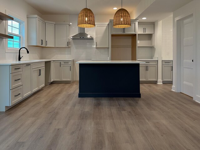 kitchen with tasteful backsplash, light wood-type flooring, pendant lighting, sink, and a center island