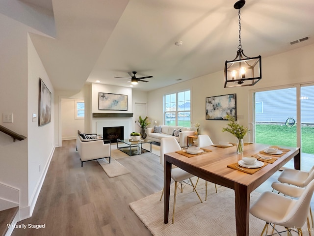 dining space featuring light wood-type flooring and ceiling fan with notable chandelier