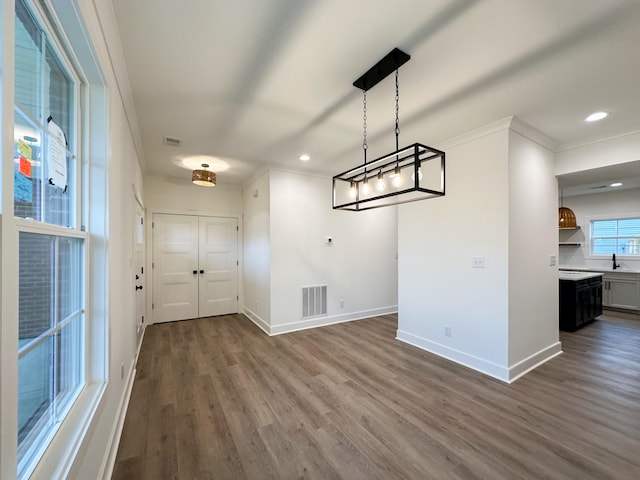 unfurnished dining area featuring ornamental molding, dark hardwood / wood-style flooring, and sink