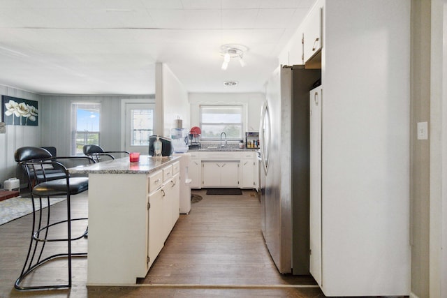 kitchen with dark hardwood / wood-style floors, light stone counters, white cabinetry, and stainless steel appliances