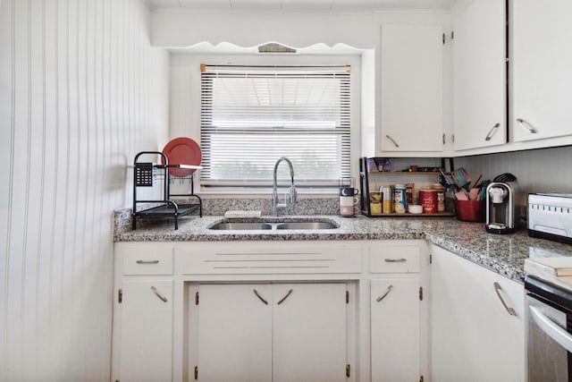 kitchen featuring dark wood-type flooring, sink, light stone countertops, appliances with stainless steel finishes, and white cabinetry