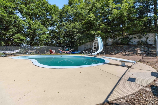 view of swimming pool with a patio area, a diving board, and a water slide