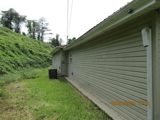 view of side of home featuring central AC unit and a lawn