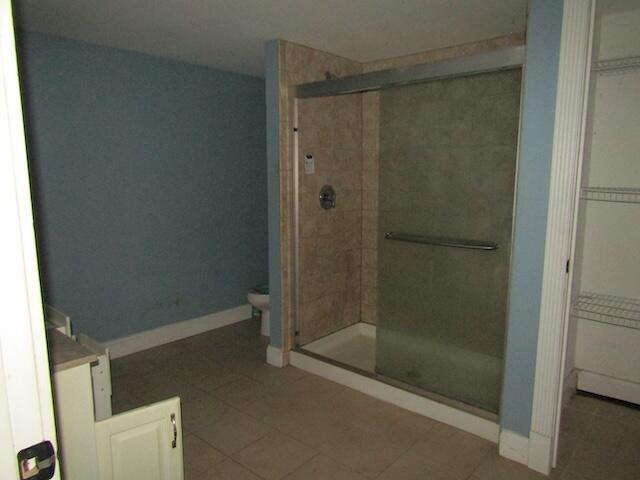 bathroom featuring tile patterned floors, toilet, and an enclosed shower