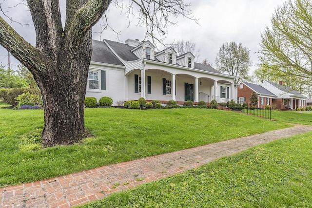 cape cod-style house with covered porch, a front lawn, and roof with shingles