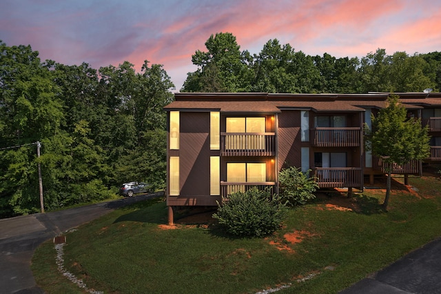 view of front of home with a yard and a balcony