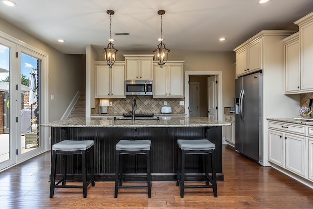 kitchen with appliances with stainless steel finishes, backsplash, and a kitchen island with sink