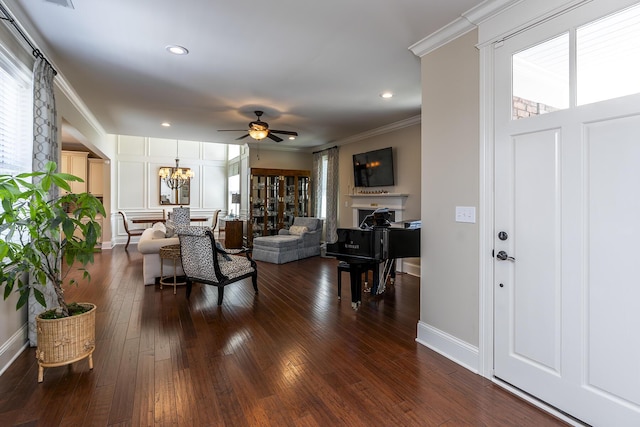 living room with ceiling fan with notable chandelier, dark hardwood / wood-style floors, and crown molding