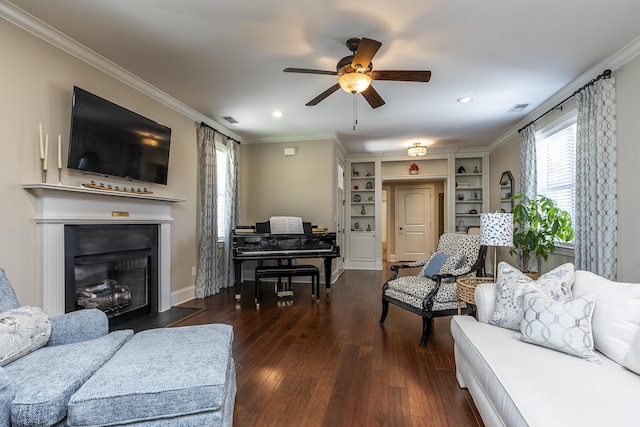 living room featuring dark hardwood / wood-style floors, built in features, ceiling fan, and crown molding