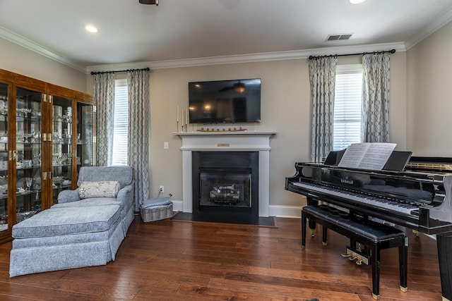 living area with dark hardwood / wood-style flooring, a healthy amount of sunlight, and ornamental molding