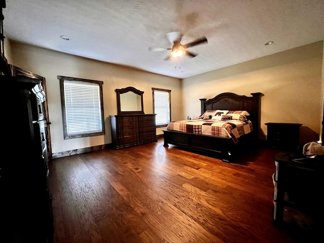 unfurnished bedroom with a textured ceiling, dark hardwood / wood-style floors, black fridge, and ceiling fan