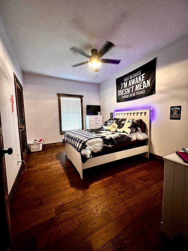 bedroom with ceiling fan, dark hardwood / wood-style flooring, and a textured ceiling