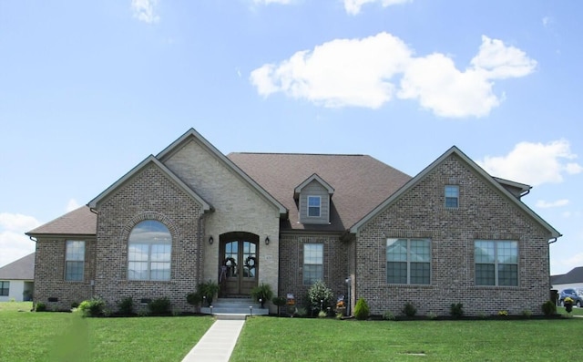 french country home with french doors, brick siding, and a front lawn