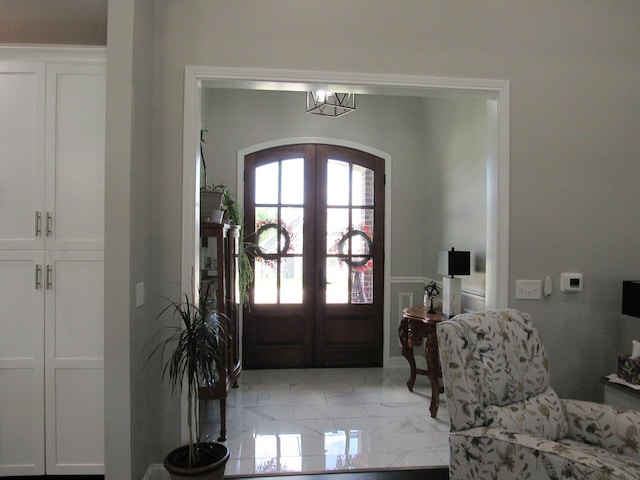 foyer entrance featuring marble finish floor, french doors, and arched walkways