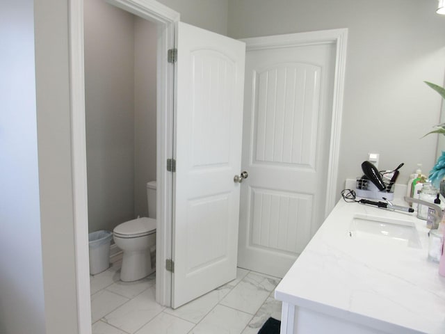 bathroom featuring toilet, marble finish floor, and vanity
