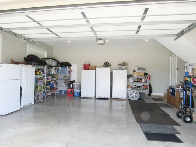 garage featuring freestanding refrigerator, white refrigerator, and a garage door opener