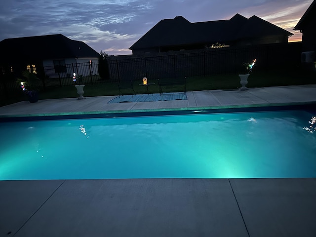 pool at dusk with fence and a fenced in pool