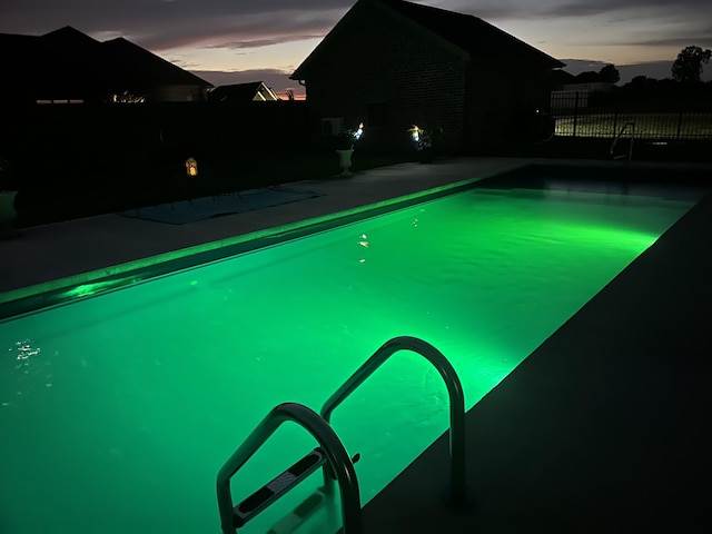pool at dusk featuring a fenced in pool and fence