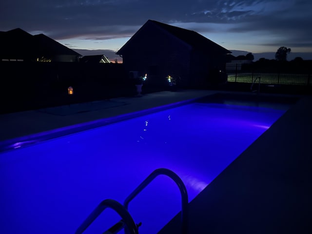 pool at dusk featuring a patio, a fenced in pool, and fence