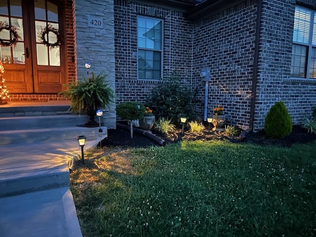 doorway to property with a yard and brick siding