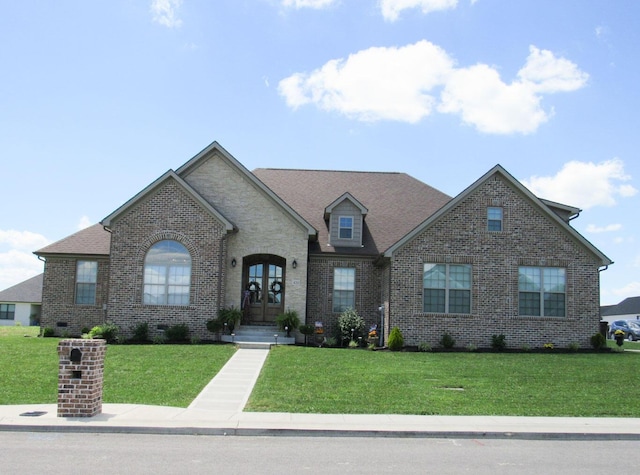 french provincial home featuring brick siding and a front yard