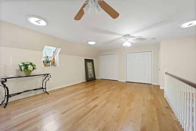 interior space featuring ceiling fan, light wood-type flooring, and lofted ceiling with skylight