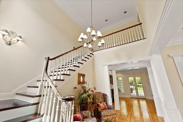 stairs featuring hardwood / wood-style floors, a notable chandelier, crown molding, and french doors