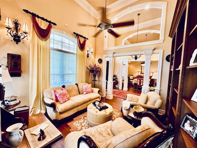 living room with ornamental molding, decorative columns, hardwood / wood-style flooring, a towering ceiling, and ceiling fan