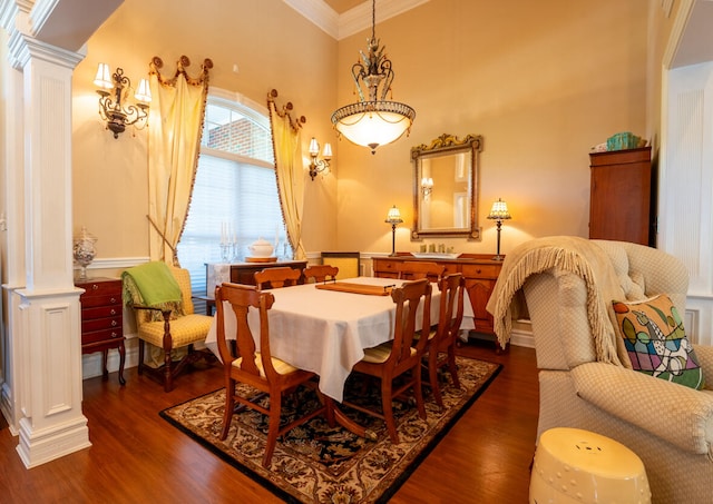 dining area featuring crown molding, dark hardwood / wood-style floors, a towering ceiling, and ornate columns