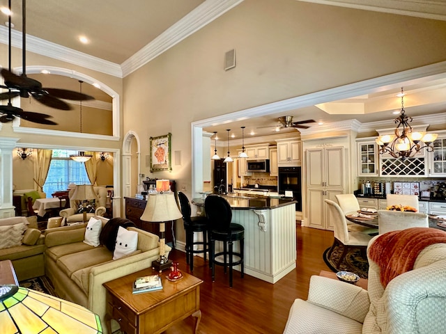 living room with dark hardwood / wood-style flooring, crown molding, and ceiling fan with notable chandelier