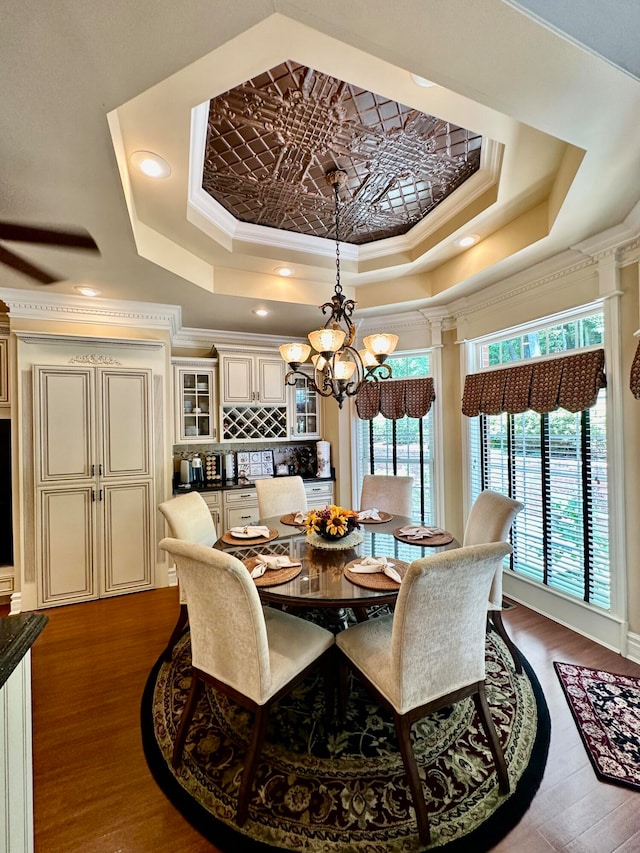 dining space with a notable chandelier, a tray ceiling, and crown molding