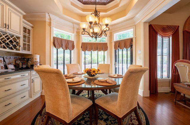 dining space with dark hardwood / wood-style flooring, a chandelier, a tray ceiling, and ornamental molding