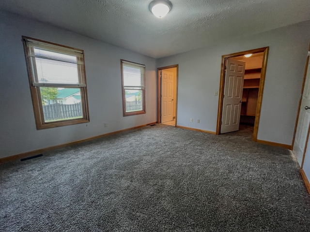 interior space featuring multiple windows, a textured ceiling, a spacious closet, and a closet